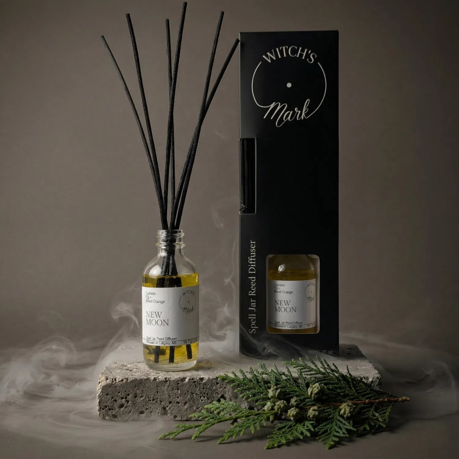 A New Moon spell jar reed diffuser by Witch's Mark showcased with its sleek black packaging and fresh cypress, emitting a continuous flame-free botanical fragrance to spark focus and clarity.