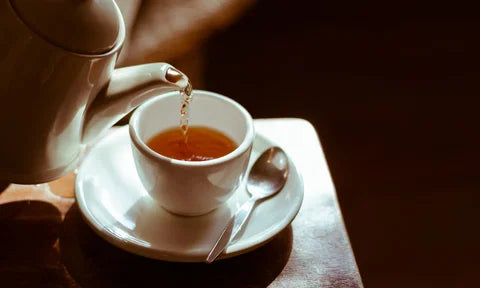 A cup of tea being poured from a teapot