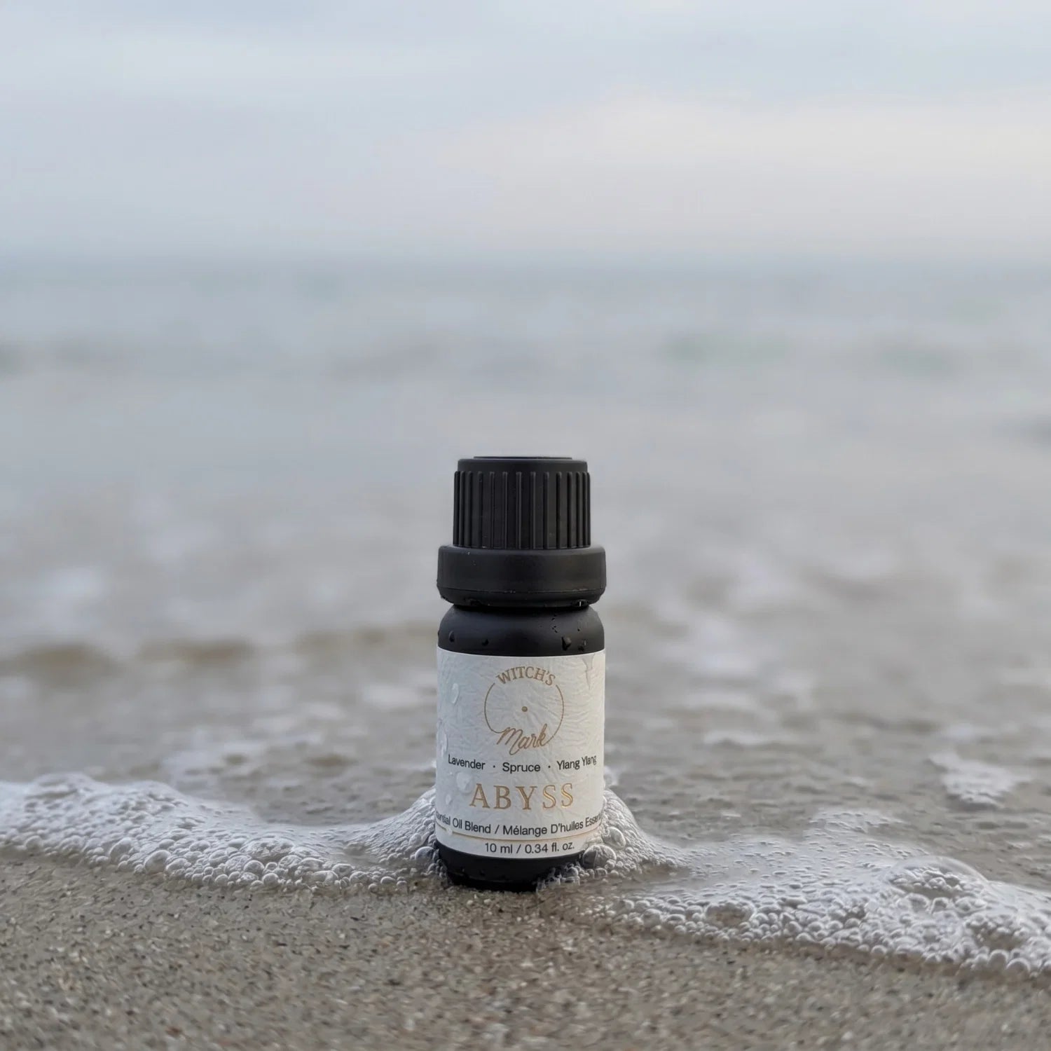 Abyss essential oil blend on a sandy beach with a wave.
