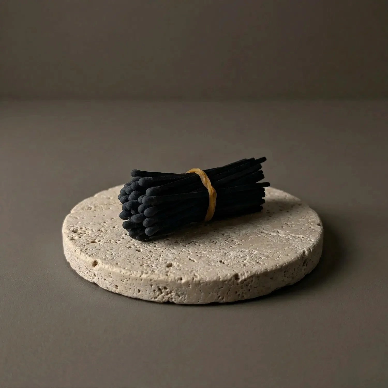 A bundle of 50 sleek black-on-black 3-inch matches resting horizontally on a textured stone coaster against a dark background. These aesthetic black matches provide a natural, traditional way to light spell candles on your witchcraft altar.