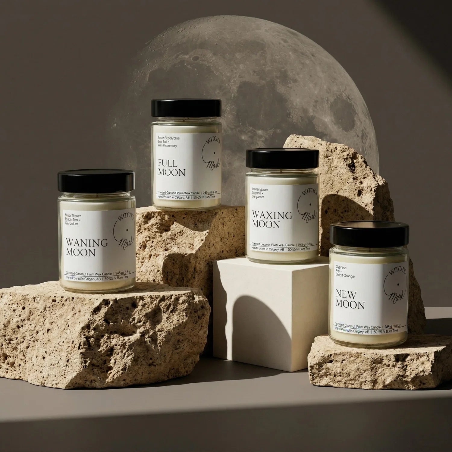 The complete Lunar Cycle Ritual Bundle by Witch's Mark, featuring the Waning, Full, Waxing, and New Moon coconut wax candles arranged on textured stones against a dramatic glowing moon backdrop.